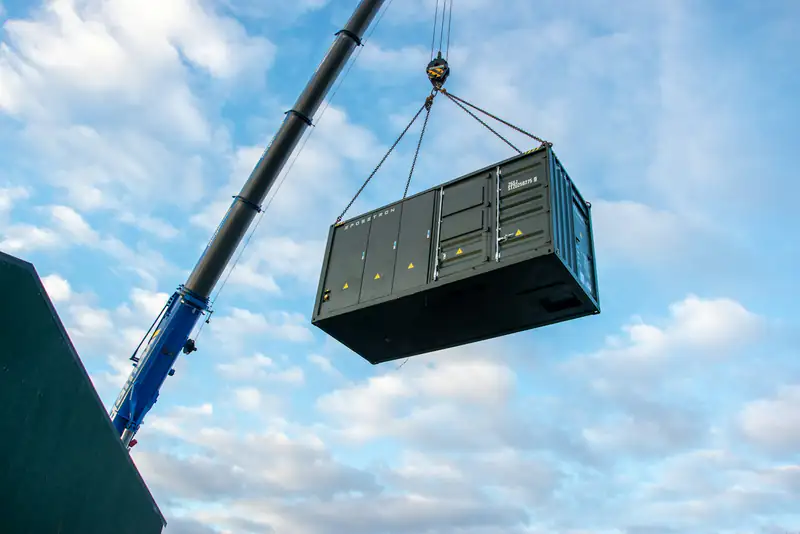 A mobile crane lifting a large container against a blue sky (stock photo)